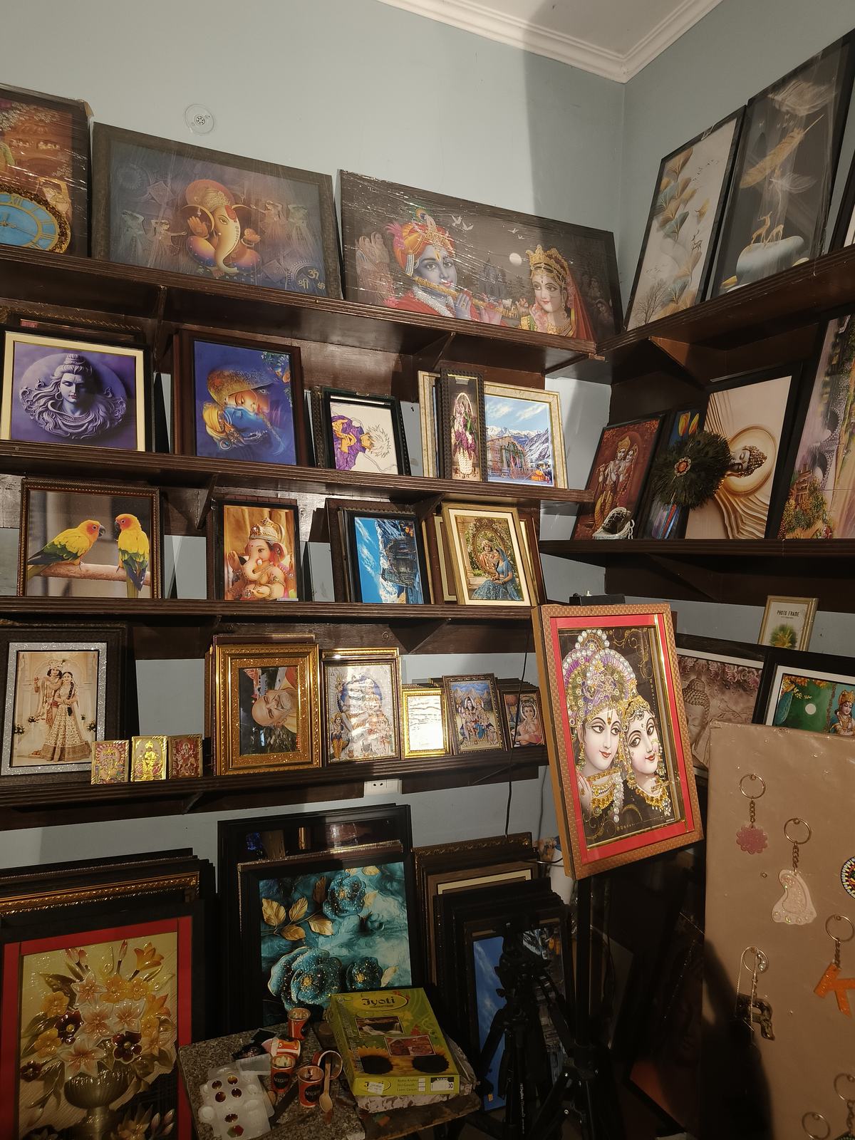 Close view of framed artwork, devotional frames, resin work, and gift items